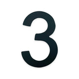 Un grand numéro noir de 7,6 cm de haut de la série Animo de yessential.fr se dresse sur un fond blanc uni - idéal comme numéro de maison sans perçage ou à combiner avec d'autres numéros de maison comme le noir 3.