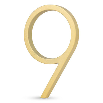 Le numéro de maison 9 Amato Gold 15 cm de yessential.fr a un design moderne de couleur dorée sur fond blanc ; parfait comme ajout élégant à votre façade.