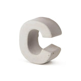 Le béton Enrico 20 cm de yessential.fr est une lettre C tridimensionnelle en béton gris clair qui se dresse sur un fond blanc uni et souligne l'apparence d'un numéro de maison élégant en béton durable.