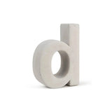 Le béton Enrico 20 cm de yessential.fr est une lettre minuscule « d » 3D en béton durable, debout sur un fond blanc - une touche élégante qui rappelle un numéro de maison moderne.