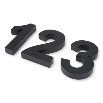 Trois numéros de maison Angelo 3D noirs de 20 cm (1, 2, 3) de yessential.fr sont placés en diagonale sur un fond blanc, chacun incliné vers le haut et vers la gauche pour un look moderne.