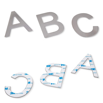 Trois lettres Animo en acier inoxydable de 5 cm de yessential.fr sont présentées, dont l'une a été retournée pour révéler le support adhésif 3M. Ces numéros de maison autocollants en acier inoxydable ne nécessitent pas de perçage et sont faciles à appliquer.