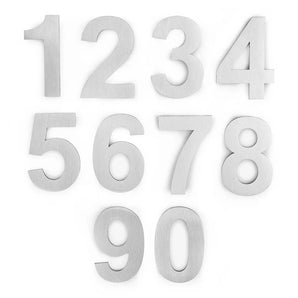 Dix chiffres métalliques (0-9) sont disposés en trois rangées sur un fond blanc. Ils ressemblent tous à l'Animo Stainless Steel 5cm (sans perceuse) de yessential.fr, avec une texture en métal brossé et un style de police élégant et moderne.