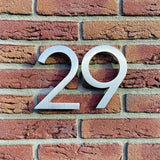 Le numéro de maison Milano en acier inoxydable 15 cm de yessential.fr est un numéro de maison moderne avec une finition brossée, parfait pour un mur de briques élégant.