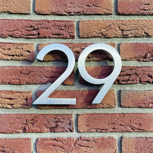 Le numéro de maison Milano en acier inoxydable 15 cm de yessential.fr est un numéro de maison moderne avec une finition brossée, parfait pour un mur de briques élégant.