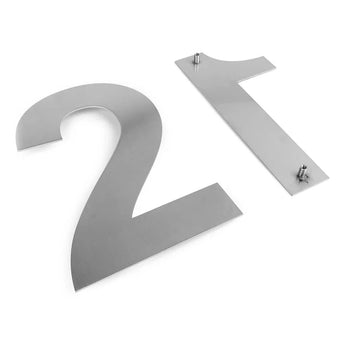 Deux numéros de maison Adamo de 15 cm en acier inoxydable (2 et 1) de yessential.fr, en acier inoxydable brossé, reposent à plat sur une surface blanche. Les poteaux de montage à l'arrière indiquent qu'ils sont prêts pour un montage mural élégant dans votre maison.