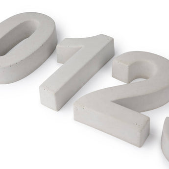 Numéros de maison Enrico en béton de 20 cm "0", "1" et "2" par yessential.fr, présentant un design en béton tridimensionnel gris bleuté avec une texture lisse - partiellement visible disposé sur un fond blanc.
