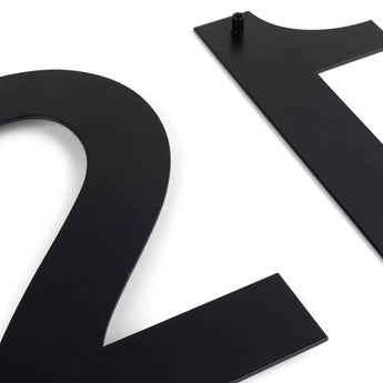 Deux numéros de maison Adamo Black 20 cm de yessential.fr, numéros 2 et 1, reposent sur un fond blanc. Le numéro 1 a une goupille de montage en haut – des numéros de façade modernes idéaux.