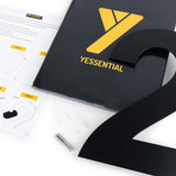 L'Adamo Black 30 cm de yessential.fr - un numéro 2 en métal noir frappant - comprend une feuille d'instructions, du matériel d'installation et une boîte noire avec le logo jaune Yessential, le tout soigneusement présenté sur une surface blanche.