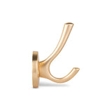 L'Eduardo Gold Deluxe de yessential.fr est un élégant crochet de couleur laiton avec deux broches incurvées sur une base ronde, sur un fond blanc uni.