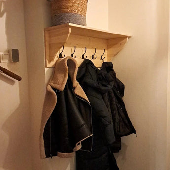 Un support mural à 2 crochets yessential.fr 10x Nismo Black permet de ranger les manteaux et les vestes dans le couloir, avec un panier tressé sur le dessus. L'éclairage tamisé crée une atmosphère chaleureuse.