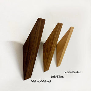 Trois patères murales Fabio Beech de yessential.fr, en noyer, chêne et hêtre (patères en bois de hêtre), sont montées sur un mur blanc. Chaque porte-manteau minimaliste porte une étiquette indiquant l'essence de bois en anglais et en néerlandais.