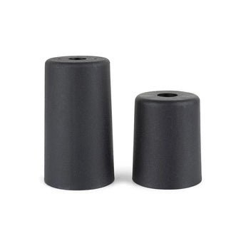 Deux bouchons cylindriques noirs en caoutchouc Sicco Black de 10 cm de yessential.fr, chacun avec un trou central et des hauteurs différentes, se tiennent debout sur un fond blanc - ils ressemblent à des pieds de meuble ronds durcis en noir.