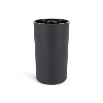 La Sicco Black 10cm de yessential.fr est une tasse cylindrique noire avec une finition mate et un bord avec un motif en croix. La tasse se tient debout sur un fond blanc et reflète le style élégant des pieds de meubles ronds noirs.
