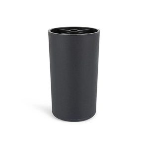 La Sicco Black 10cm de yessential.fr est une tasse cylindrique noire avec une finition mate et un bord avec un motif en croix. La tasse se tient debout sur un fond blanc et reflète le style élégant des pieds de meubles ronds noirs.