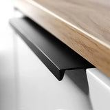 Un gros plan de la poignée de tiroir Enzo Black de yessential.fr, une poignée d'angle moderne en métal noir, montée sur une armoire blanche avec un comptoir en bois clair au-dessus.