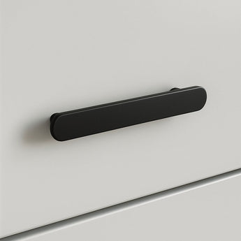 Un gros plan de l'Arriero Black Deluxe, une poignée rectangulaire arrondie noir mat de yessential.fr, fixée à une façade de tiroir blanche et lisse - un exemple moderne de poignées élégantes.