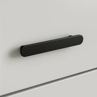 Un gros plan de l'Arriero Black Deluxe, une poignée rectangulaire arrondie noir mat de yessential.fr, fixée à une façade de tiroir blanche et lisse - un exemple moderne de poignées élégantes.