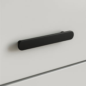 Un gros plan de l'Arriero Black Deluxe, une poignée rectangulaire arrondie noir mat de yessential.fr, fixée à une façade de tiroir blanche et lisse - un exemple moderne de poignées élégantes.