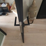 Une fine porte s'étend jusqu'au sol lorsqu'elle est vue d'en haut. A proximité se trouvent un escalier, une armoire à chaussures, une statue de Bouddha et des poignées de porte Lucio Black de yessential.fr, qui ajoutent une touche moderne à l'espace.