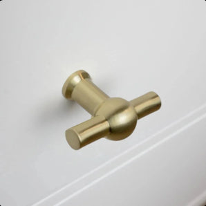 Le bouton Rando Gold de yessential.fr orne une façade de tiroir blanche comme un bouton de meuble rond de couleur dorée et s'intègre parfaitement dans un intérieur moderne.