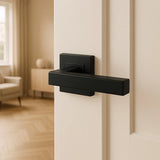 Un grand plan pour la porte Domaso Noir yessential.fr avec les béquilles noires sur une porte blanche, et un plan intérieur d'un salon avec un fauteuil beige et du parquet.