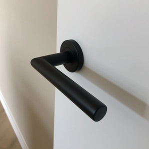 La finition de la porte Lucio Black de yessential.fr est montée sur une porte blanche, avec un mur beige et un plan parquet et bois. Une façon très élégante d'adopter un style moderne et d'importer un intérieur.