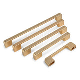 Quatre poignées d'armoires de cuisine Ramiro Gold Deluxe de yessential.fr, de différentes longueurs, sont disposées en diagonale sur un fond blanc, la plus petite poignée étant à l'avant.