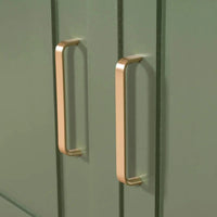 Gros plan des poignées Leonardo Gold Deluxe de yessential.fr sur des portes d'armoires vertes avec un design à rainure verticale, ajoutant un style de cuisine de luxe.