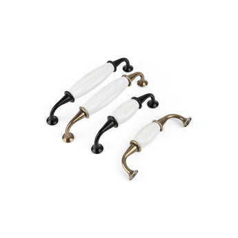 Quatre poignées de meuble Daro Ceramic Black de yessential.fr avec céramique blanche au centre et extrémités incurvées noires ou laiton, placées en diagonale sur fond blanc.