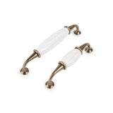 Deux poignées de meuble Daro Ceramic Antique Gold de yessential.fr, avec des extrémités incurvées en métal bronze et de la céramique blanche au centre, se dressent en diagonale sur un fond blanc.