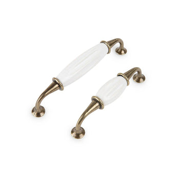 Deux poignées de meuble Daro Ceramic Antique Gold de yessential.fr, avec des extrémités incurvées en métal bronze et de la céramique blanche au centre, se dressent en diagonale sur un fond blanc.