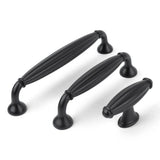 Trois boutons noirs Alvaro de yessential.fr, avec un design ovale nervuré et une base évasée de différentes longueurs, offrent un look de bouton de meuble classique - élégamment affiché sur un fond blanc.