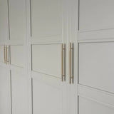 Portes d'armoire à panneaux blancs au design géométrique minimaliste, équipées d'élégantes poignées dorées Remo Gold Deluxe de yessential.fr pour une touche moderne.