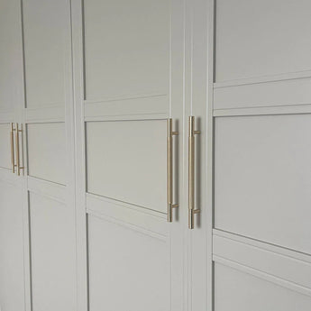 Portes d'armoire à panneaux blancs au design géométrique minimaliste, équipées d'élégantes poignées dorées Remo Gold Deluxe de yessential.fr pour une touche moderne.