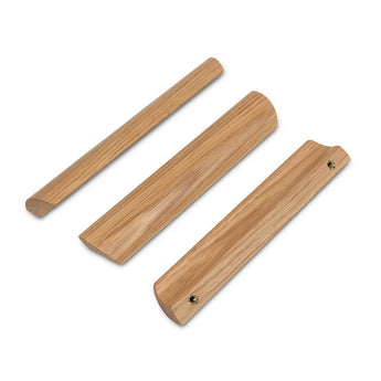 Trois butées de porte en bois de différentes formes et rainures, présentées sur fond blanc. Fabriquées en chêne clair avec des surfaces lisses, elles s'accordent parfaitement avec les poignées Lucasso Oak de yessential.fr.