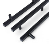 Trois poignées Marano Black de yessential.fr, à la finition noire mate épurée et aux supports cylindriques, sont placées en diagonale sur un fond blanc.