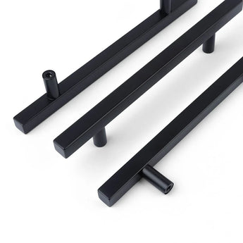 Trois poignées Marano Black de yessential.fr, à la finition noire mate épurée et aux supports cylindriques, sont placées en diagonale sur un fond blanc.