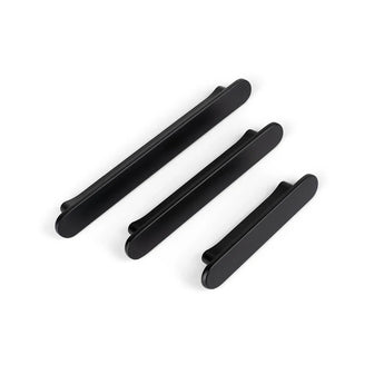 Trois poignées Arriero Black Deluxe de yessential.fr de différentes longueurs sont disposées en diagonale sur un fond blanc et ajoutent un style moderne à n'importe quelle armoire ou tiroir.