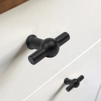 Gros plan du bouton Rando noir en forme de T de yessential.fr avec finition noir mat sur un tiroir blanc, avec un bouton identique sur le tiroir du dessous.