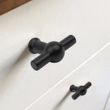 Gros plan du bouton Rando noir en forme de T de yessential.fr avec finition noir mat sur un tiroir blanc, avec un bouton identique sur le tiroir du dessous.