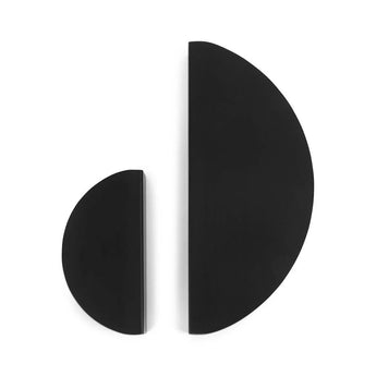 Deux poignées semi-circulaires noires Torno Black de yessential.fr se dressent debout sur un fond blanc, leurs côtés plats se faisant face avec un espace entre eux, rappelant les poignées en demi-lune.