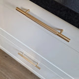 Gros plan de deux tiroirs Remo Gold Deluxe de yessential.fr, avec d'élégantes poignées dorées, sur un comptoir sombre et un parquet clair.