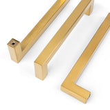 Trois poignées Vasco Gold de yessential.fr, avec un design moderne et minimaliste, des bords nets et une finition brossée lisse, sont disposées sur un fond blanc pour un look élégant et contemporain.