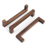 Trois poignées en noyer Vasco de yessential.fr au design minimaliste et angulaire sont présentées sur un fond blanc. Chaque pièce rectangulaire varie en taille et comporte des trous de vis visibles aux deux extrémités pour une fixation facile.