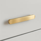 Une élégante poignée de tiroir Arriero Gold Deluxe de yessential.fr est montée horizontalement sur une armoire blanche lisse. Avec des coins arrondis et une finition dorée brossée, le design minimaliste ajoute une touche de luxe.