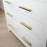Le buffet Marano Gold de yessential.fr dispose de trois tiroirs avec des poignées de meuble modernes horizontales dorées, placés sur un plancher en bois clair pour un look élégant et moderne.