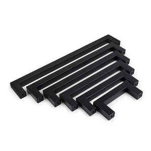 Un ensemble de six poignées de cuisine rectangulaires noires Vasco Black de yessential.fr, disposées par taille décroissante et disposées parallèlement sur un fond blanc.