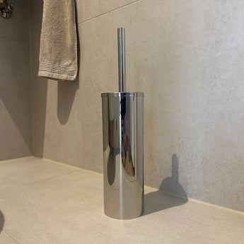 L'ensemble de toilettes Ludo Chrome (sans perçage) de yessential.fr se dresse sur un sol carrelé de salle de bain près d'un mur beige, avec une serviette beige en arrière-plan - facile à installer sans perçage.