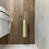 L'ensemble WC Lorenzo Gold de yessential.fr est monté sur un mur avec des panneaux en bois à côté de toilettes blanches dans une salle de bain moderne avec sol et murs carrelés gris.